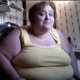A morbidly obese woman is viewed from the waist up as she sits on the toilet taking a piss and shit with subtle poop sounds. She also smokes a cigarette and uses her cell phone. About 3 minutes.